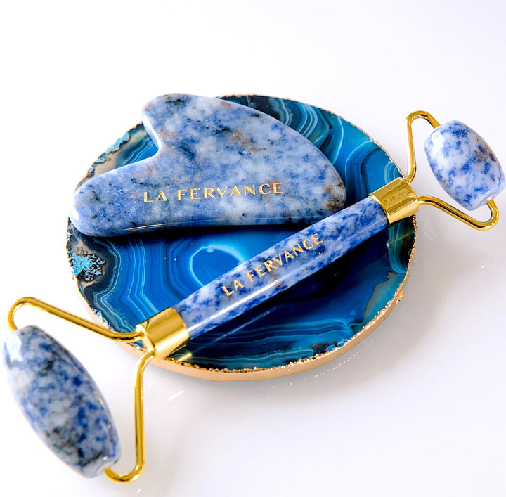 La Fervance blue face roller and gua sha on blue plate on white background