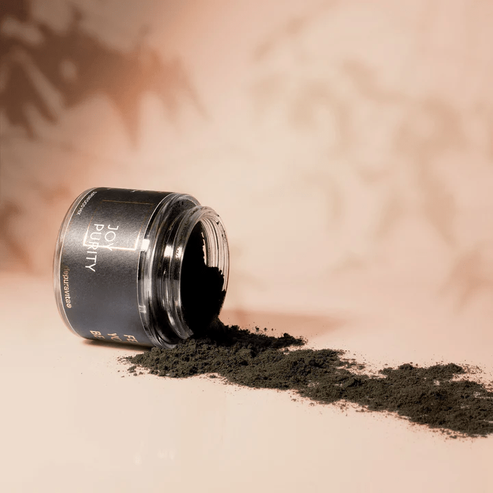 Depuravita Joy Purity jar opened with black powder on beige background