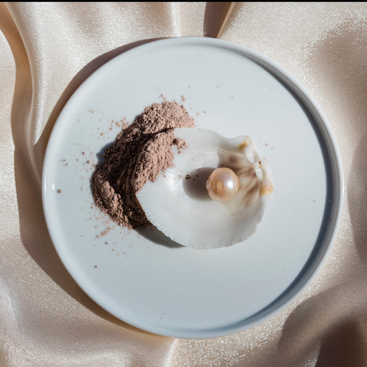 Leahlani Kokoleka Purifying Mask brown texture on white plate with shell and pearl
