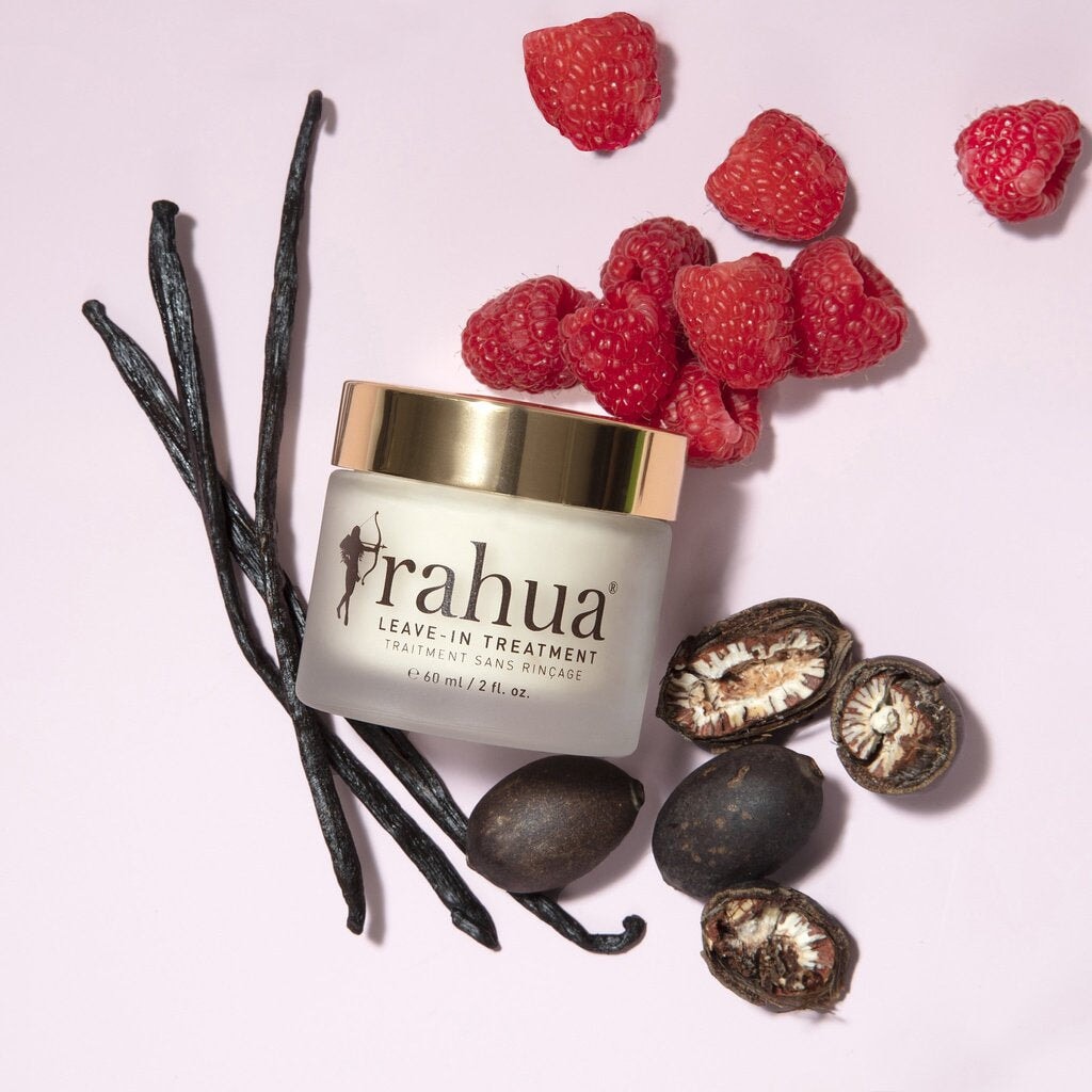 Rahua Leave-In Treatment jar with screw-on lid and texture sample against a pink background, decorated with cinnamon sticks, raspberries and nuts. North Glow