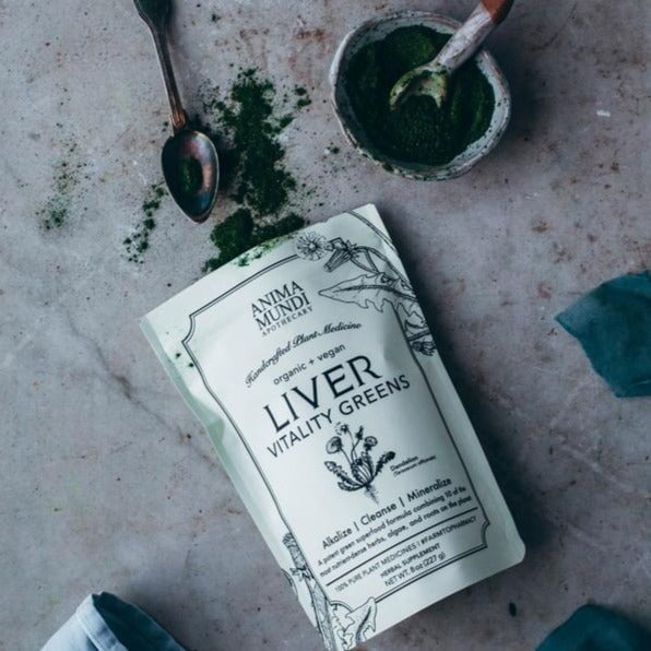 Anima Mundi Liver Verpackung aus der grünes Pulver auf grauem Untergrund ausgekippt wurde. North Glow
