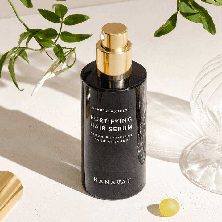 Ranavat Mighty Majesty Hair Serum Bottle on White Background with Green Leaves and Grape