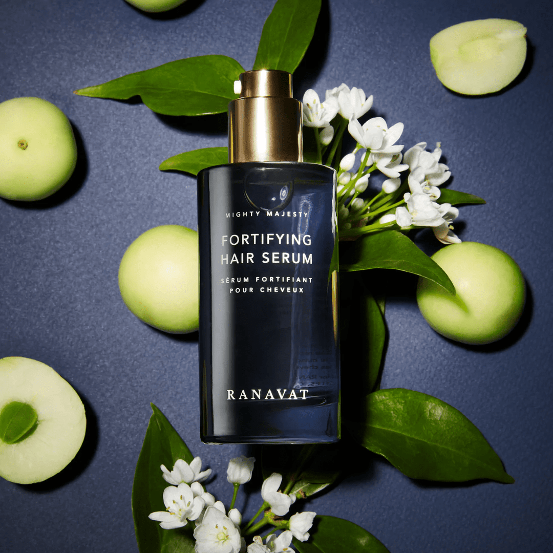Ranavat Mighty Majesty hair serum on blue background with leaves, white flowers and green apples