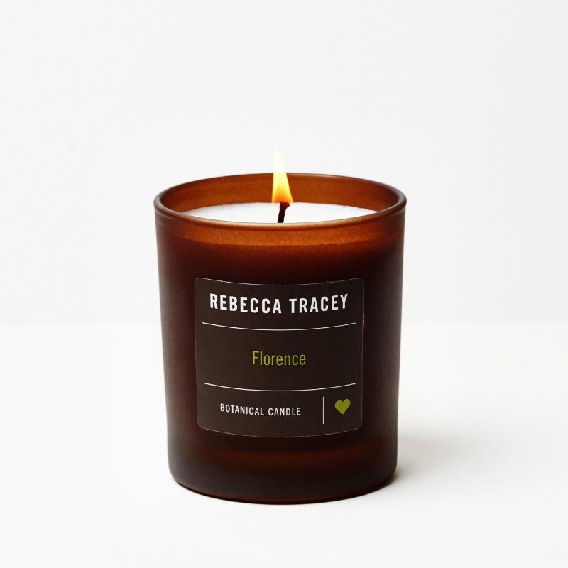Burning candle "Florence" in a glass by Rebecca Tracey against a white background.