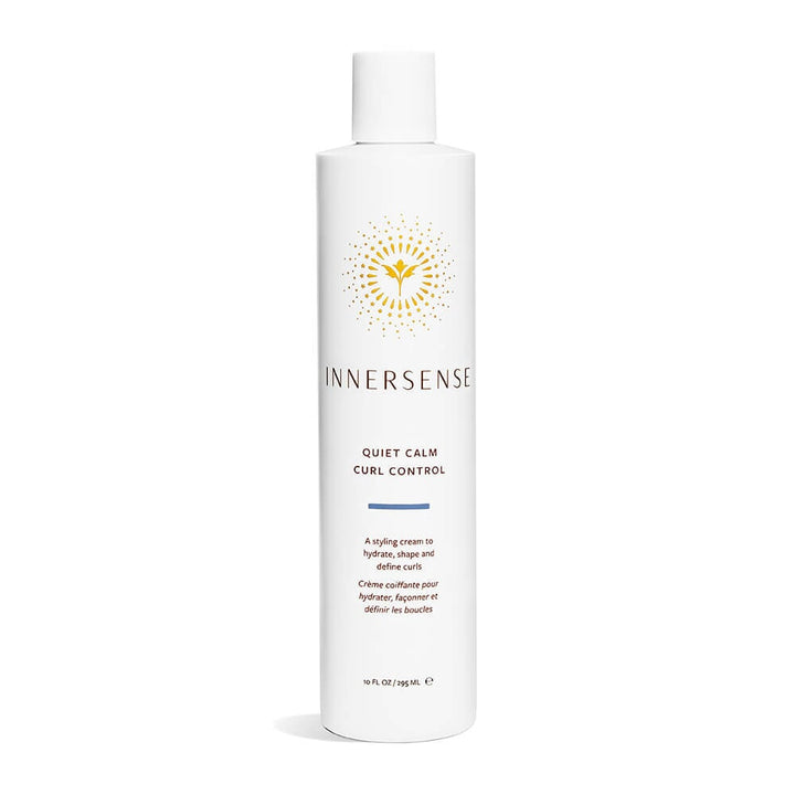 A bottle of Innersense Quiet Calm Curl Control stands in front of a white background.